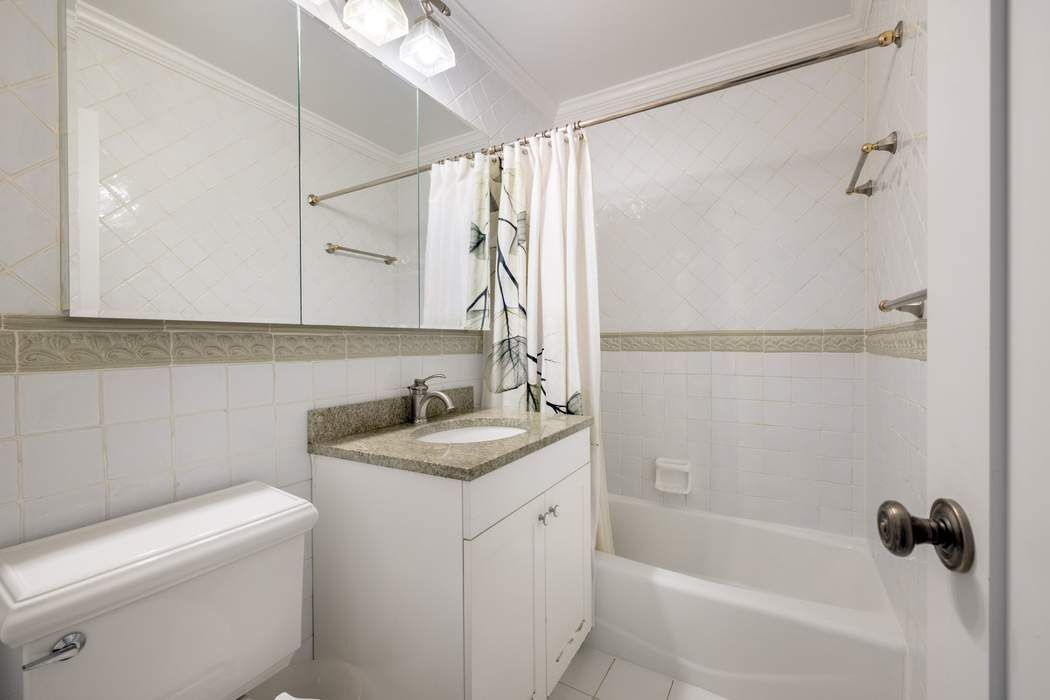 501 East 79th Street, Unit 14E Manhattan, NY 10075 - Photo 12 of 19 a bathroom with a granite countertop sink a toilet and shower