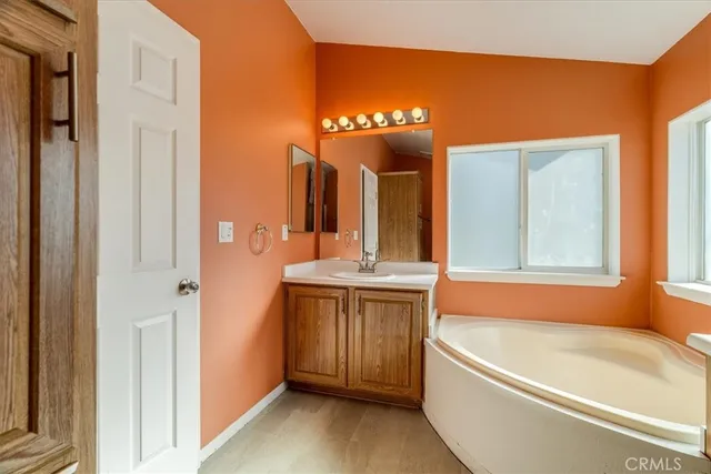 a bathroom with a tub a sink and a large mirror