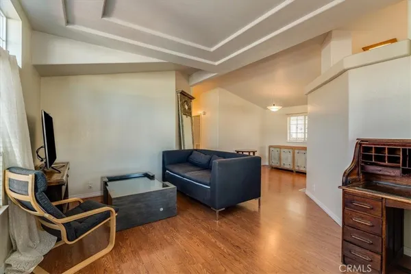 a living room with couches and a flat screen tv with kitchen view