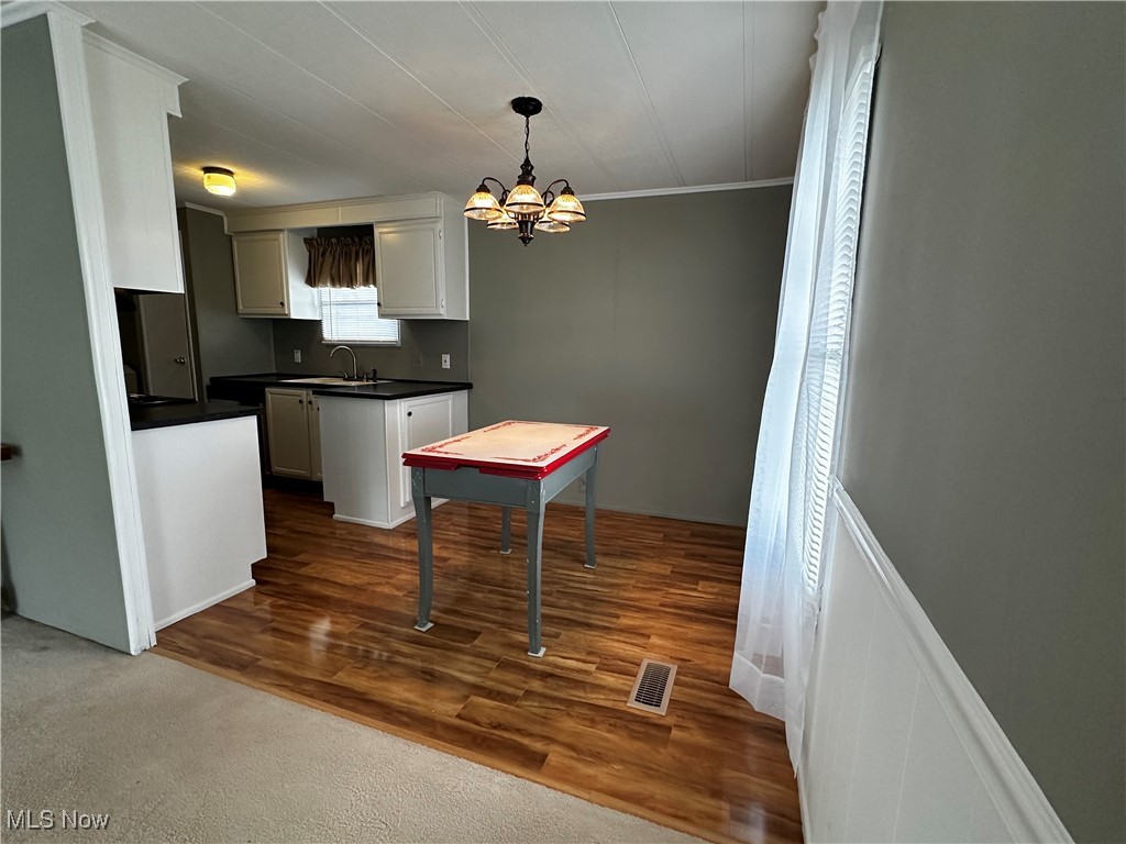 12921 Springfield Road, Unit 12S New Springfield, OH 44443 - Photo 2 of 25 Dining area featuring wood like floor, an inviting chandelier, ornamental molding, sink, and pendant lighting