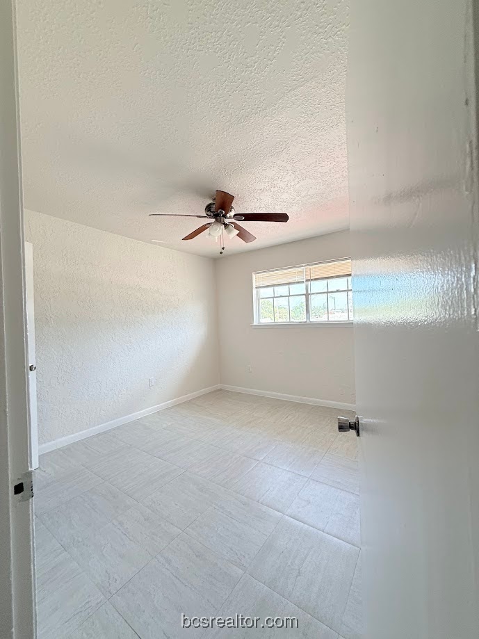 3300 South College Avenue, Unit B4 Bryan, TX 77801 - Photo 7 of 7 Unfurnished room featuring a textured ceiling and a ceiling fan