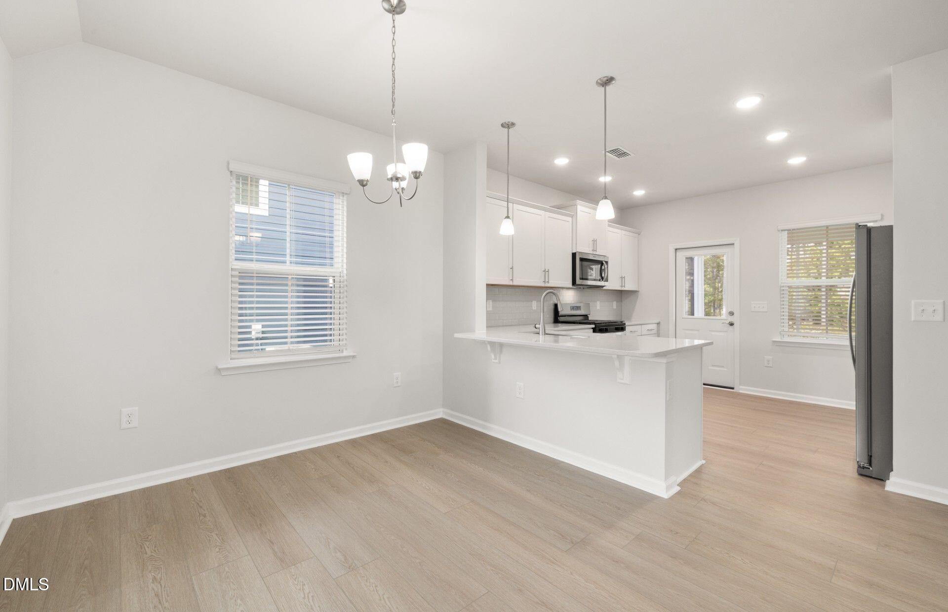 637 Fosterton Cottage Way Raleigh, NC 27603 - Photo 2 of 31 a view of an empty room and kitchen with window wooden floor and a kitchen view