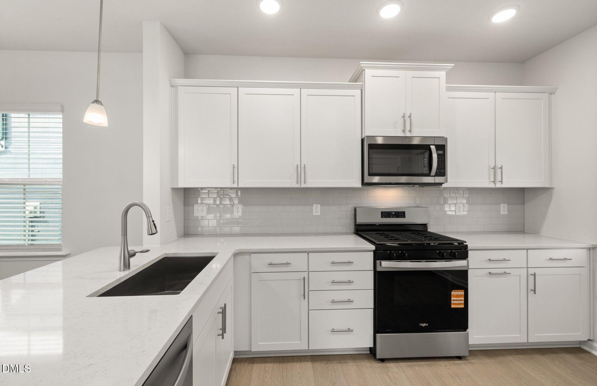 637 Fosterton Cottage Way Raleigh, NC 27603 - Photo 3 of 31 a kitchen with stainless steel appliances granite countertop a sink a stove a microwave and cabinets