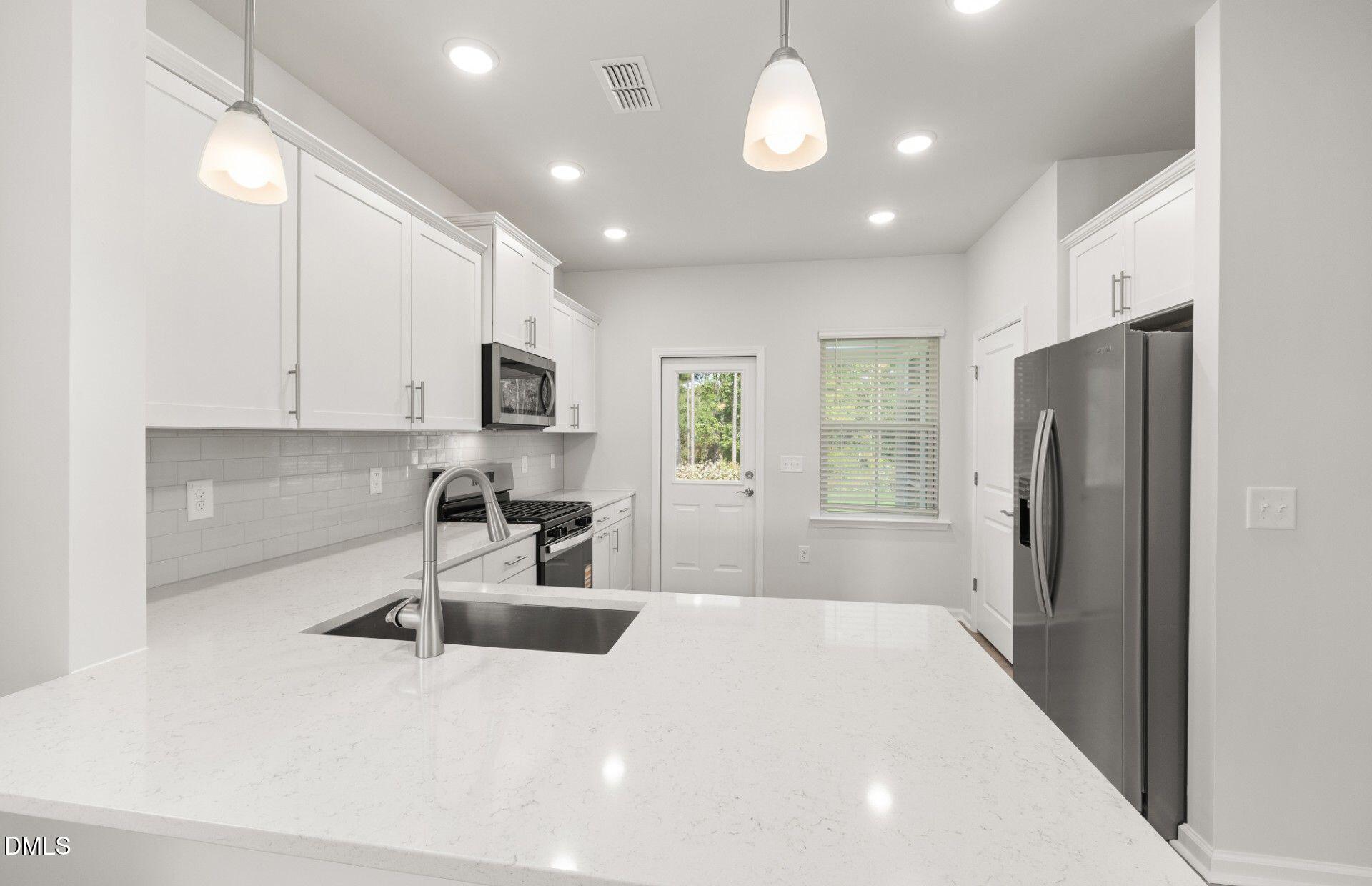 637 Fosterton Cottage Way Raleigh, NC 27603 - Photo 5 of 31 a kitchen with stainless steel appliances a refrigerator sink and microwave