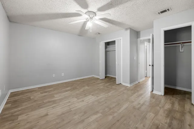 an empty room with closet and a ceiling fan