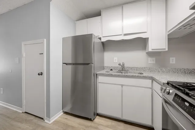a kitchen with stainless steel appliances granite countertop a refrigerator a sink and white cabinets