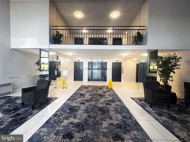 a living room with stainless steel appliances granite countertop furniture a rug kitchen view and a chandelier