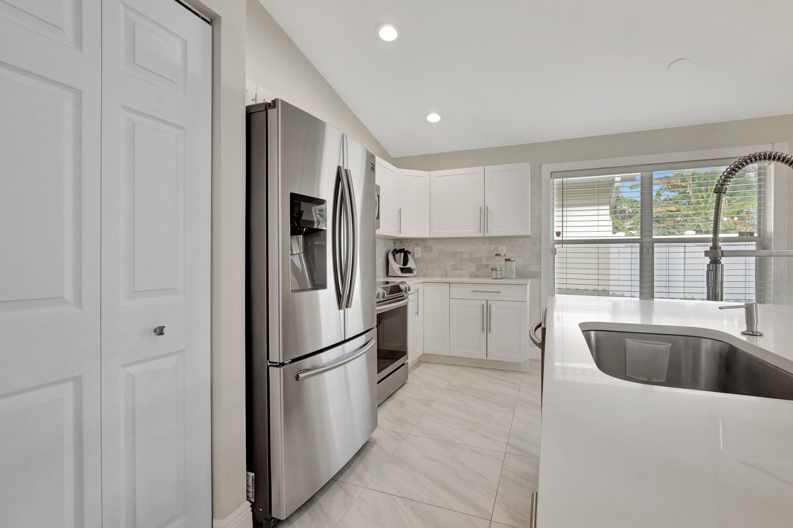 12204 Sunset Point Circle Wellington, FL 33414 - Photo 14 of 40 a kitchen with a refrigerator a sink and cabinets
