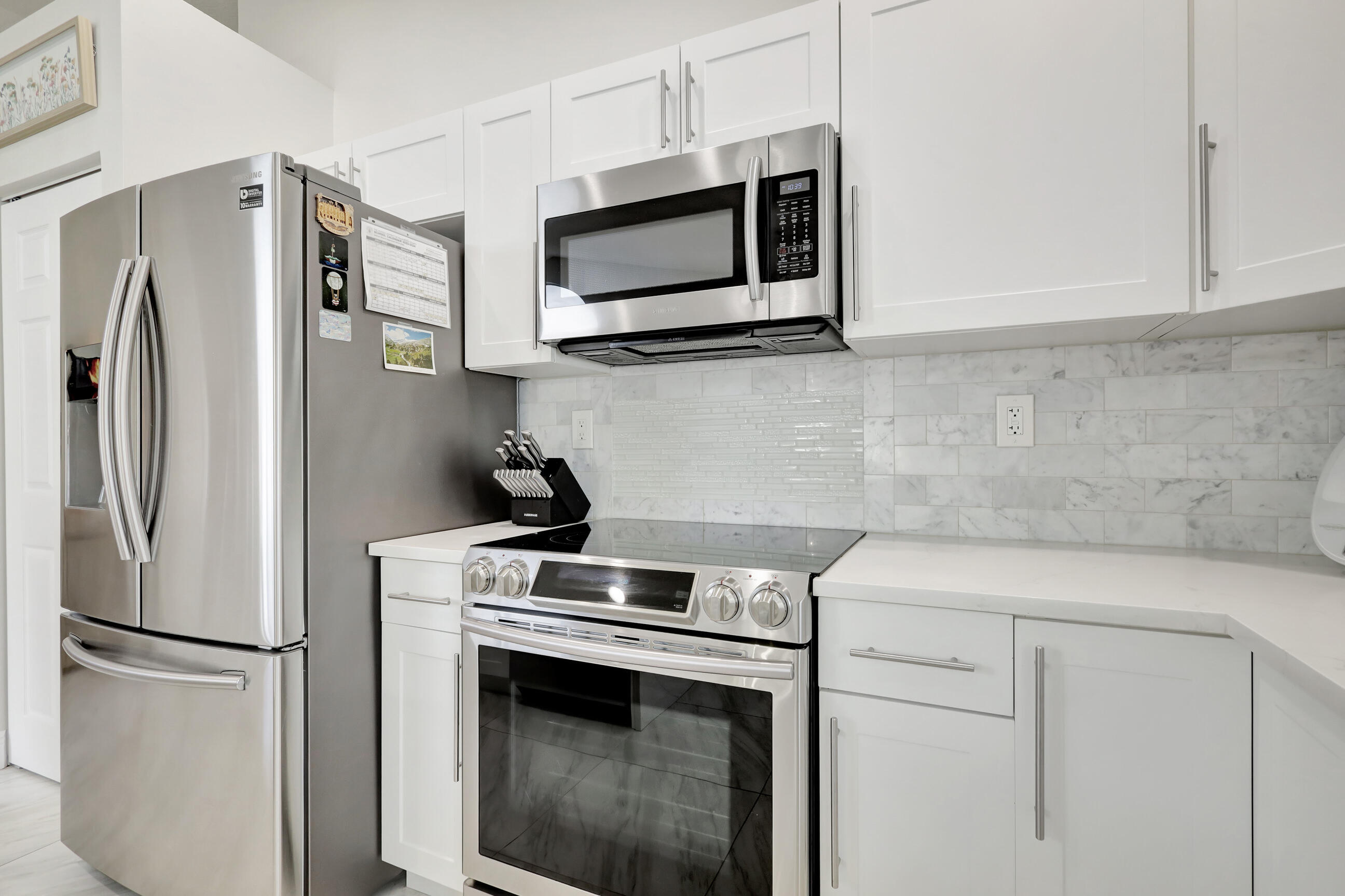 12204 Sunset Point Circle Wellington, FL 33414 - Photo 15 of 40 a kitchen with stainless steel appliances white cabinets white stove a microwave and a refrigerator