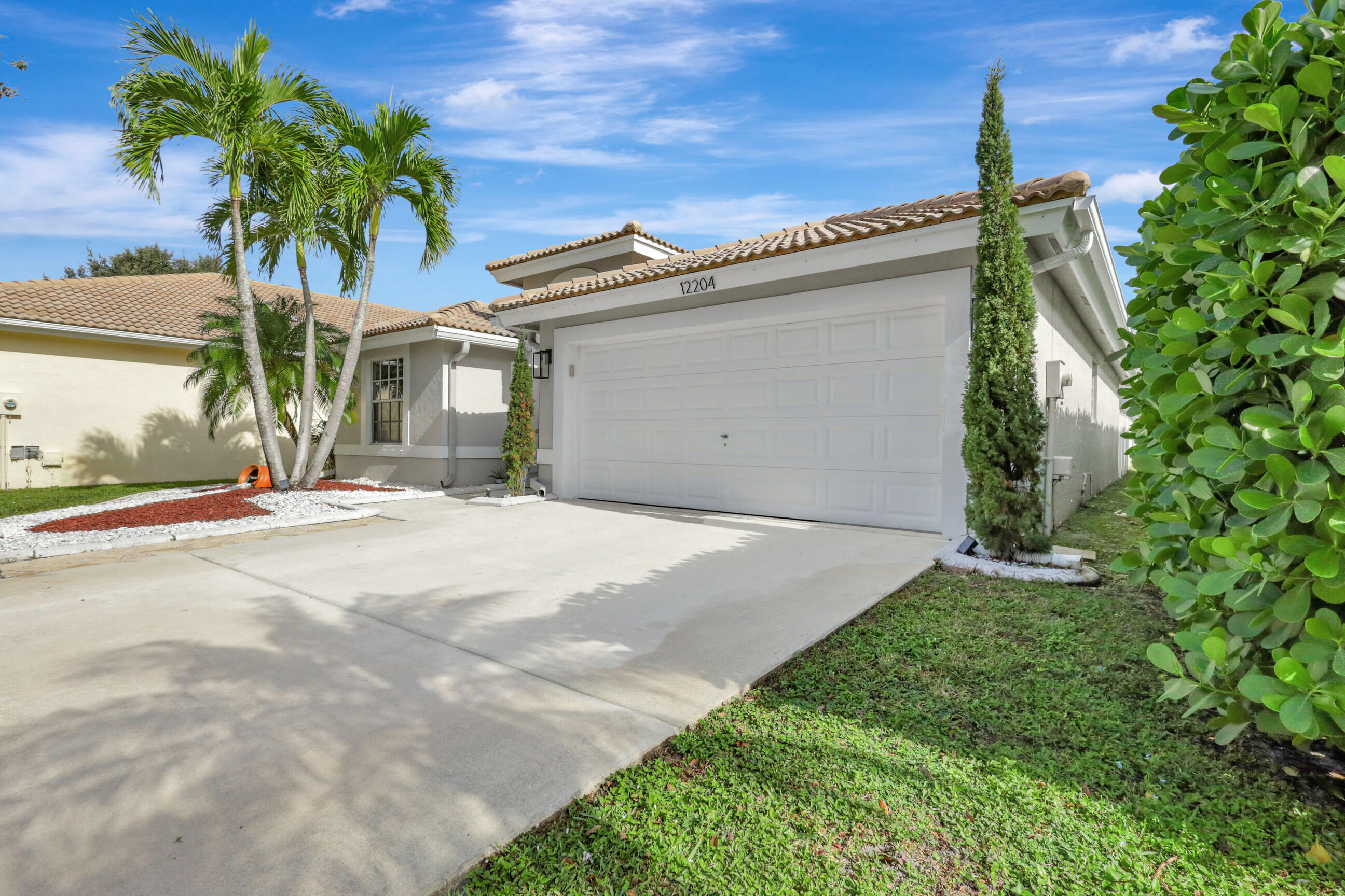 12204 Sunset Point Circle Wellington, FL 33414 - Photo 2 of 40 a front view of a house with a yard and garage