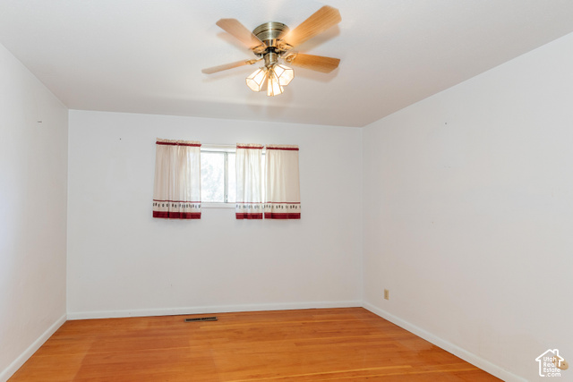 3959 Main Street Logan, UT 84321 - Photo 13 of 35 Hardwood-style flooring, white painted walls, window with a light-filtering curtain, and a ceiling fan with integrated lighting