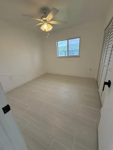 en empty room with windows and ceiling fan