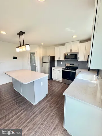 a kitchen with a wooden floor stove top oven and refrigerator