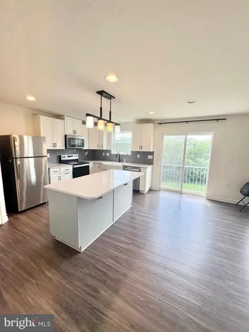 a kitchen with stainless steel appliances a stove top oven a sink cabinets and a wooden floor