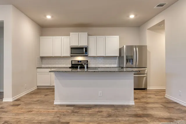 a kitchen with stainless steel appliances granite countertop a refrigerator a stove a sink and a microwave