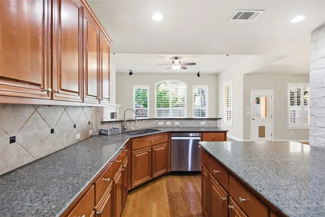 a kitchen with stainless steel appliances granite countertop a sink a stove and cabinets