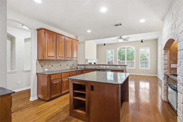 a kitchen with kitchen island granite countertop wooden floors and wide window