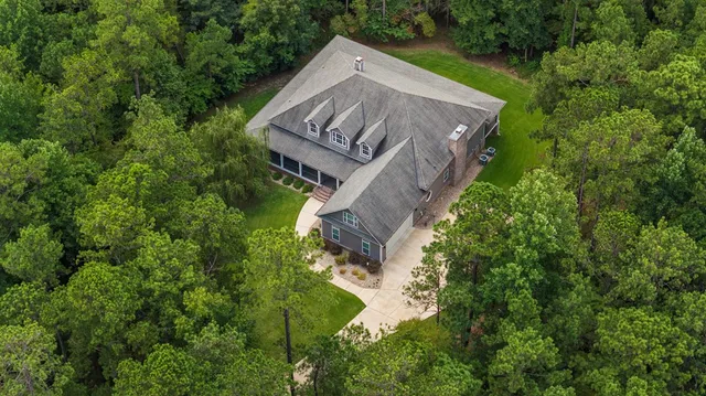 an aerial view of a house with a yard and large trees