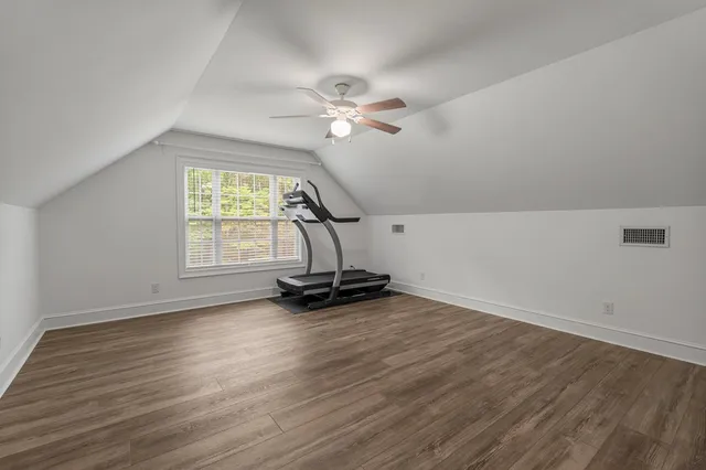 an empty room with wooden floor a ceiling fan and windows