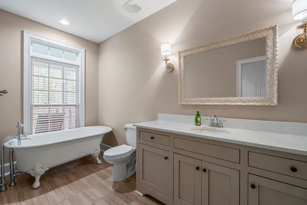 a spacious bathroom with a granite countertop sink a toilet a mirror and a window