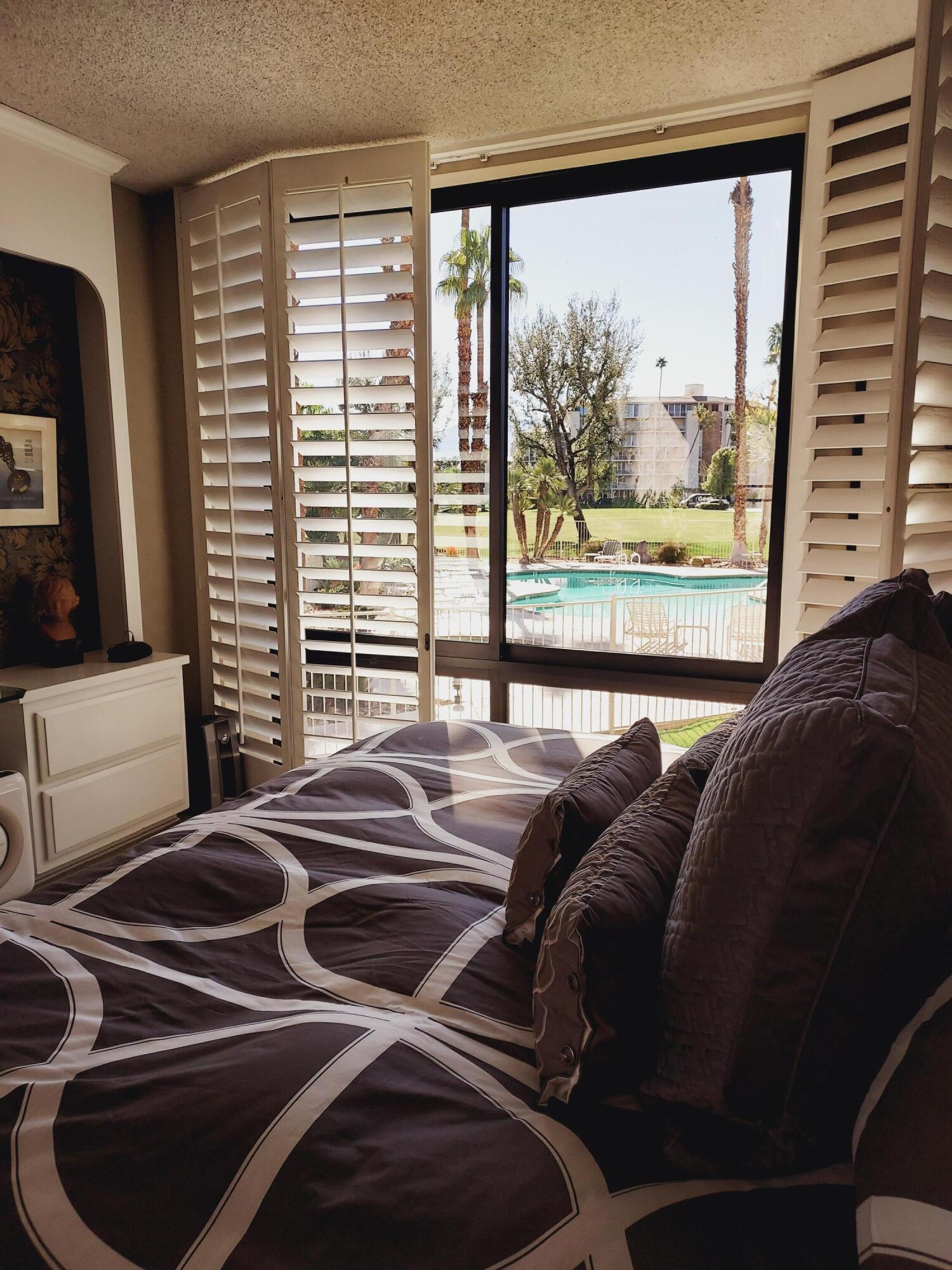 910 Island Drive, Unit 113 Rancho Mirage, CA 92270 - Photo 22 of 40 a bedroom with a bed and a large window