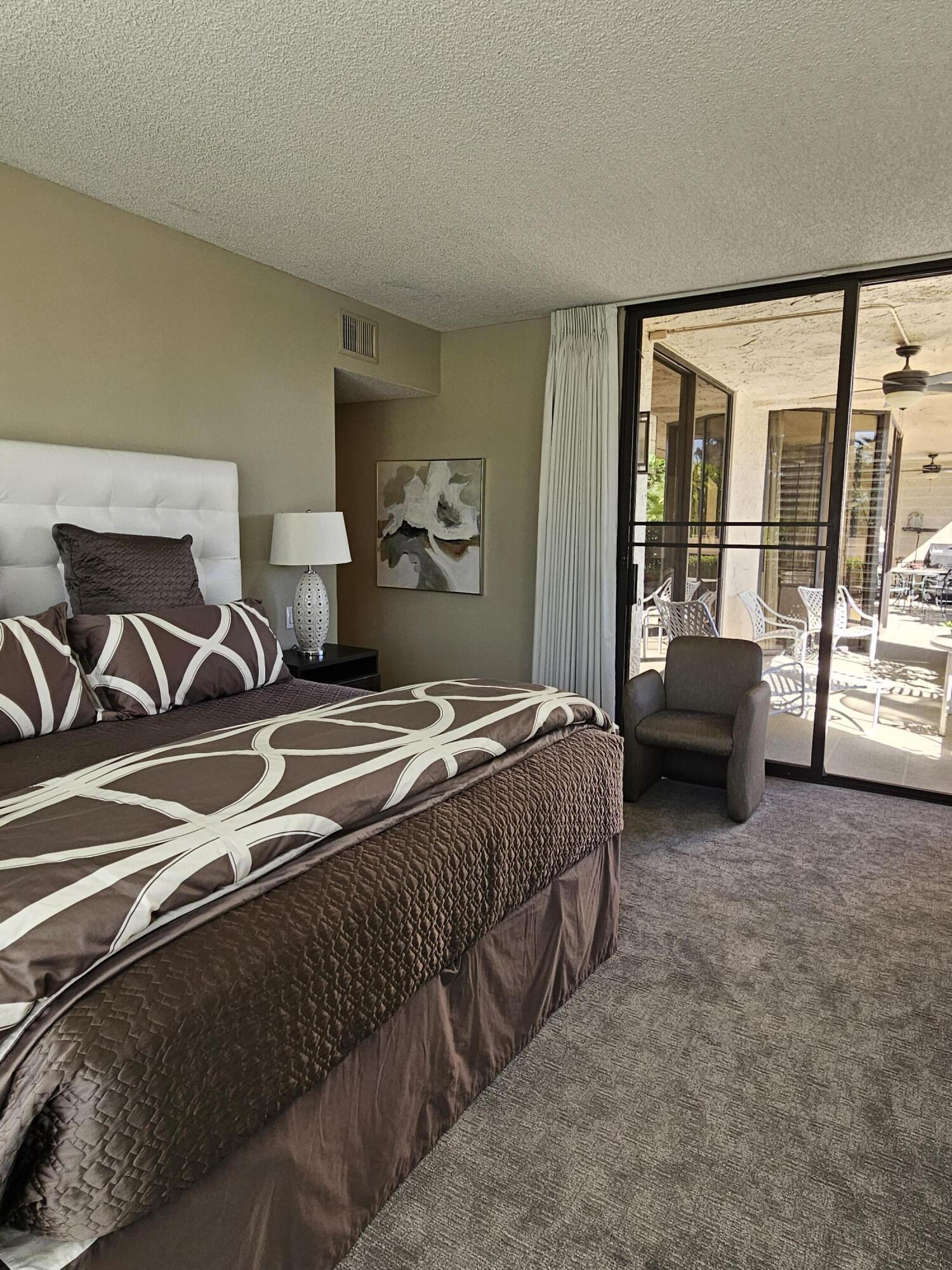 910 Island Drive, Unit 113 Rancho Mirage, CA 92270 - Photo 23 of 40 a bedroom with a bed and glass door