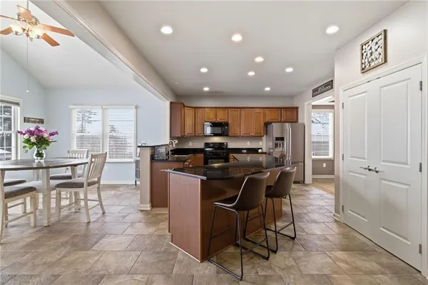 a kitchen with stainless steel appliances kitchen island granite countertop a refrigerator a stove a sink dishwasher with a dining table and chairs