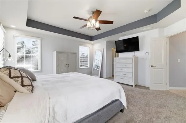 a spacious bedroom with a large bed a flat tv screen and dresser