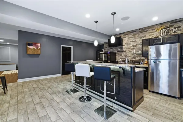 a kitchen with stainless steel appliances granite countertop a sink a stove a refrigerator cabinets and chairs