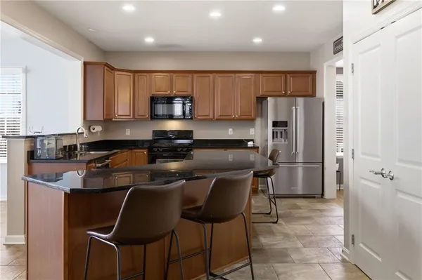 a kitchen with stainless steel appliances granite countertop a stove a sink a refrigerator white cabinets and a refrigerator