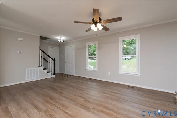 a view of an empty room with wooden floor and a window