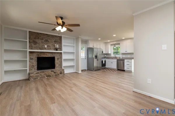 a view of a livingroom with a fireplace a ceiling fan and wooden floor