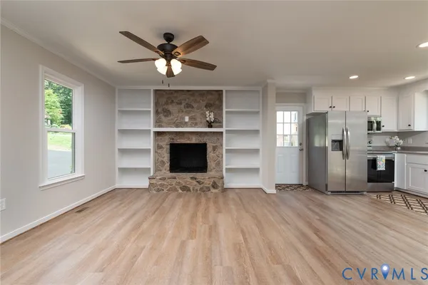 a view of an empty room with a kitchen and a window