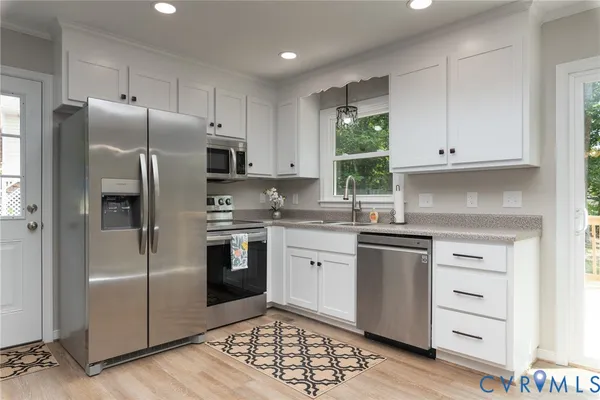 a kitchen with granite countertop white cabinets and stainless steel appliances