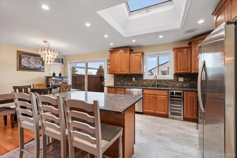 a kitchen with granite countertop lots of wooden cabinets a refrigerator a stove a dining table and chairs