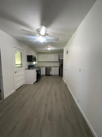 an empty room with wooden floor a ceiling fan and windows