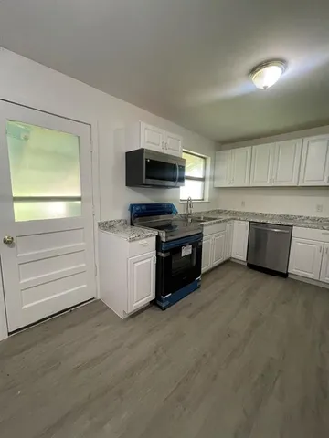 a kitchen with granite countertop a stove top oven and cabinets