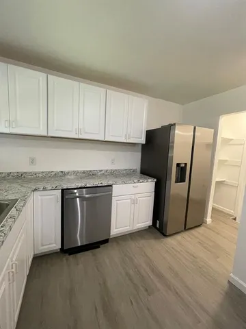 a kitchen with granite countertop white cabinets a refrigerator and a stove