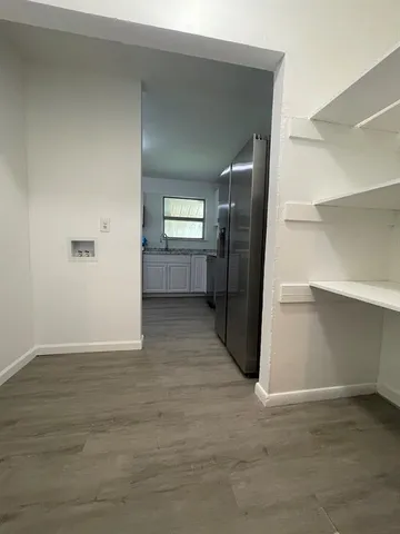 a view of a hallway with wooden floor and a refrigerator