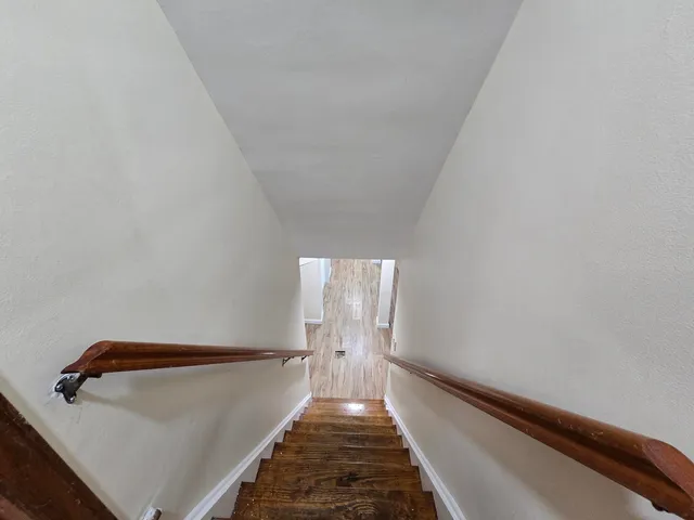 a view of a hallway with wooden floor and chandelier