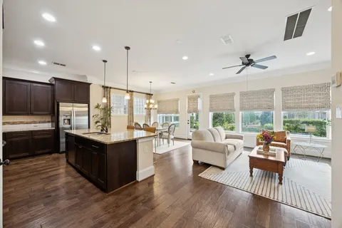 a kitchen with stainless steel appliances granite countertop a refrigerator a stove a sink dishwasher a dining table and chairs with wooden floor