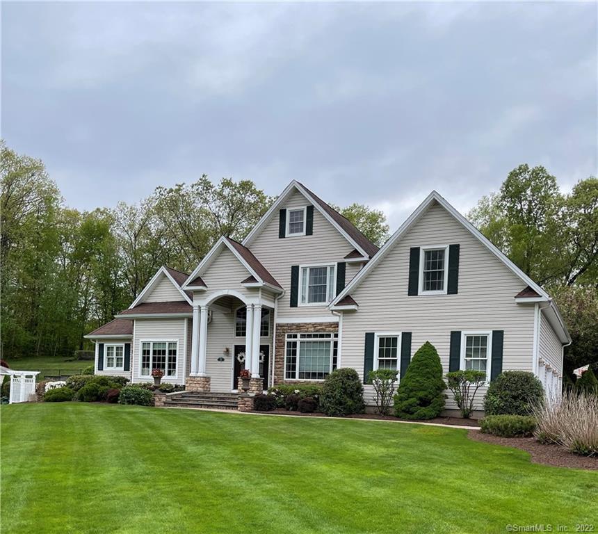 a front view of a house with a garden and trees
