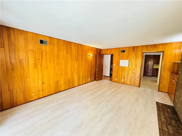a view of an empty room with wooden floor and furniture
