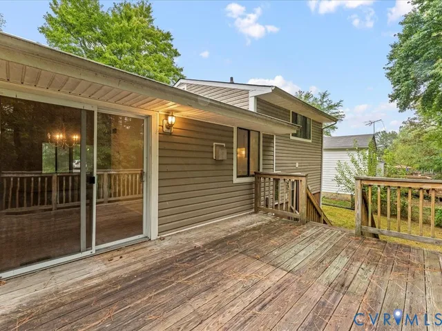 a view of a house with a wooden deck and a floor to ceiling window