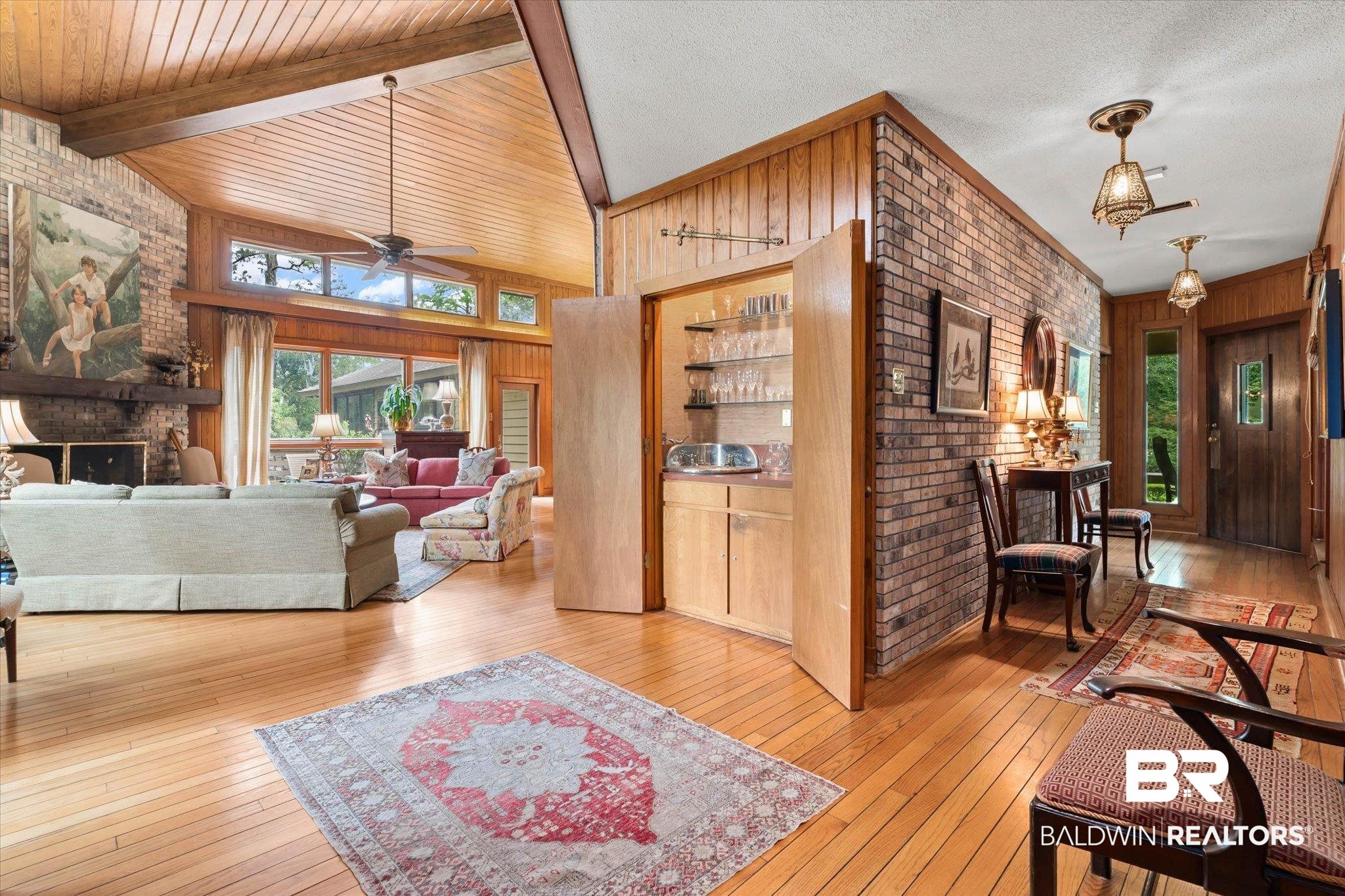 3500 Venetia Road Mobile, AL 36605 - Photo 4 of 56 Spacious living area featuring a vaulted wood-paneled ceiling with exposed beams, wood-finish flooring, a brick fireplace, and a built-in wet bar with glass shelving