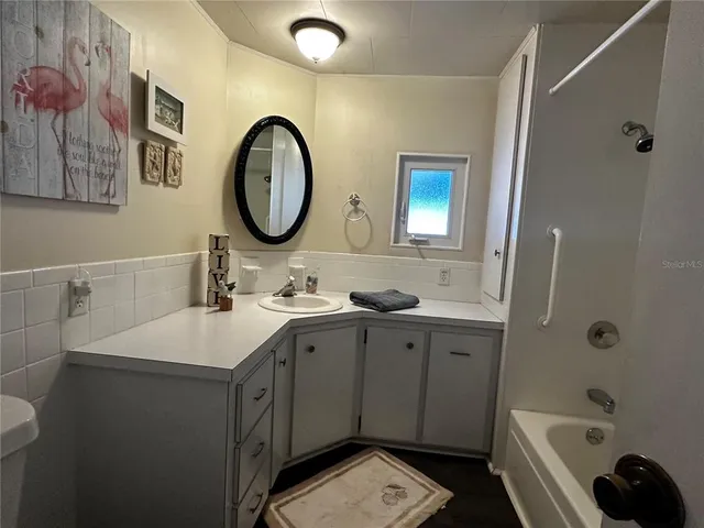 a bathroom with a tub a sink and a large mirror