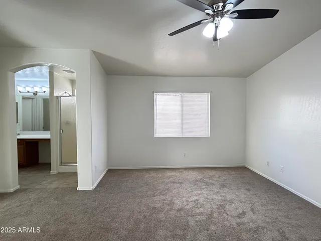 an empty room with a chandelier fan and windows