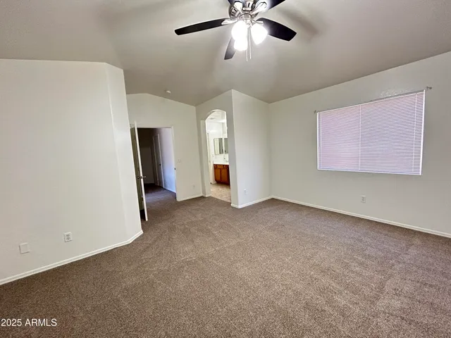 an empty room with chandelier fan and windows
