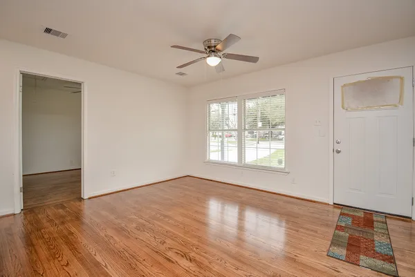 a view of an empty room with wooden floor and a window