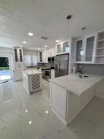a large kitchen with kitchen island a sink stainless steel appliances and cabinets